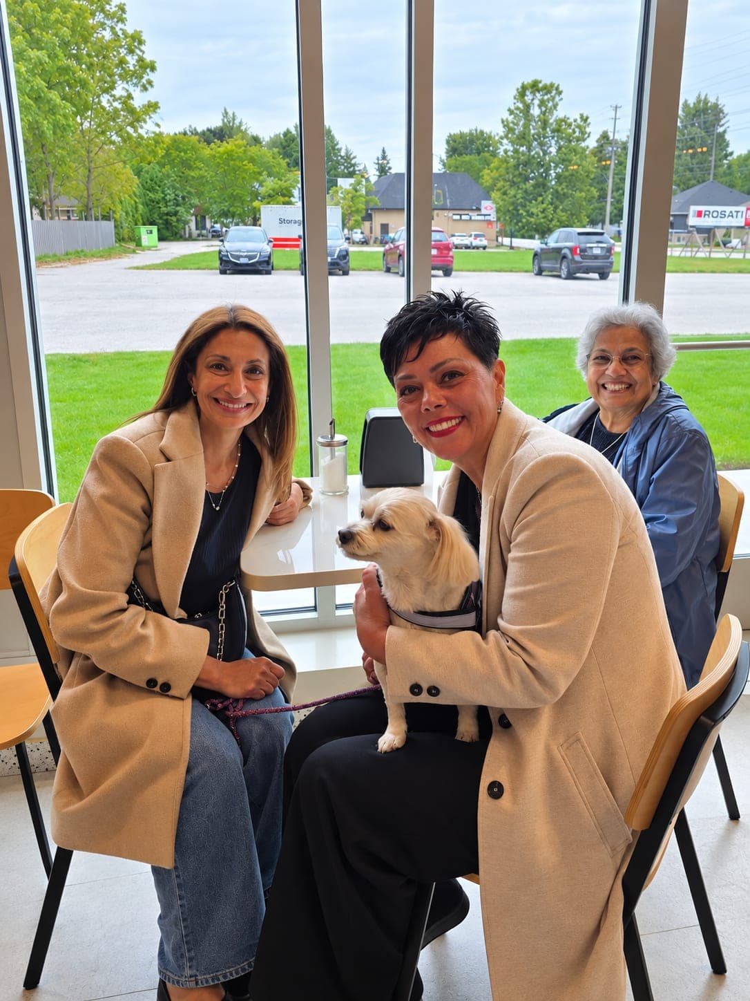 Ivana White sitting with two residents and a small dog by the window at Amici.