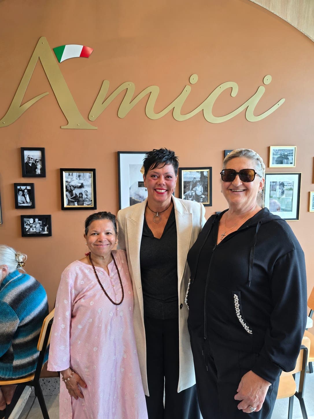 Ivana White with two residents in front of the Amici sign.
