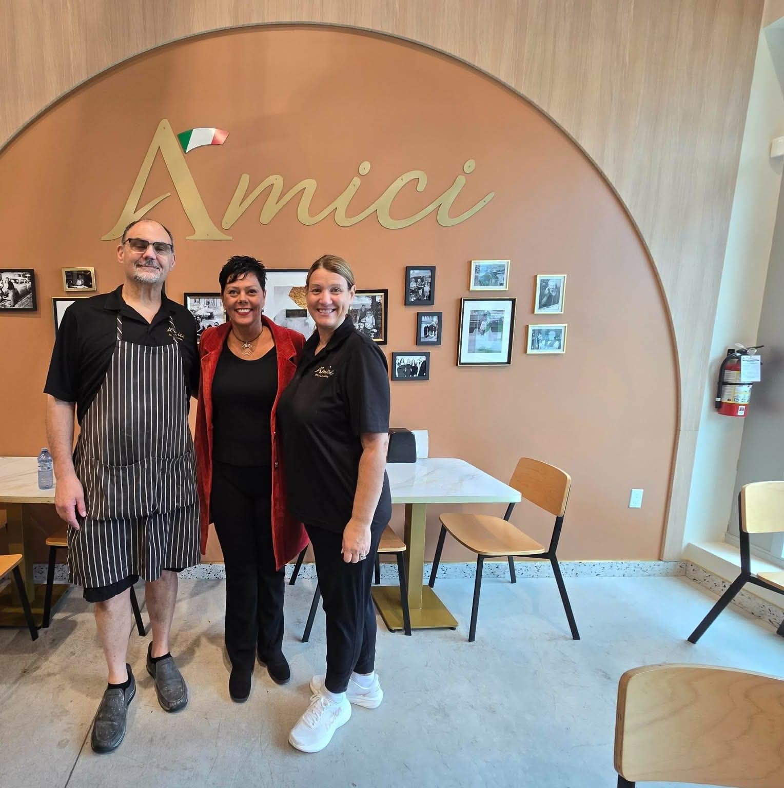 Ivana White with Vince and Sandy, the owners of Amici Deli & Bakery, in front of the Amici sign.